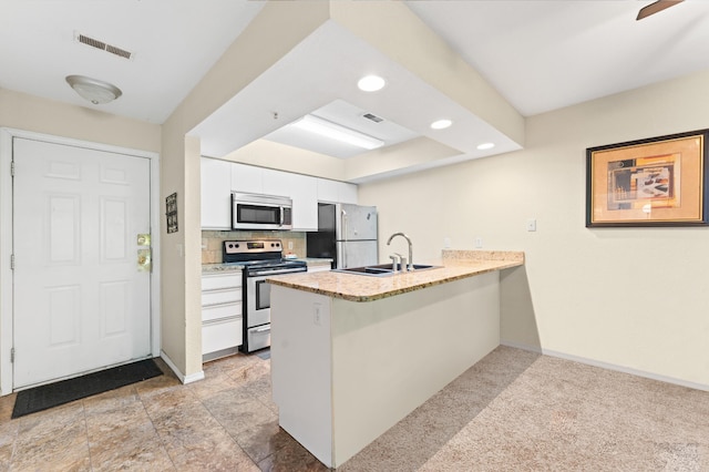 kitchen featuring white cabinets, sink, kitchen peninsula, stainless steel appliances, and light colored carpet