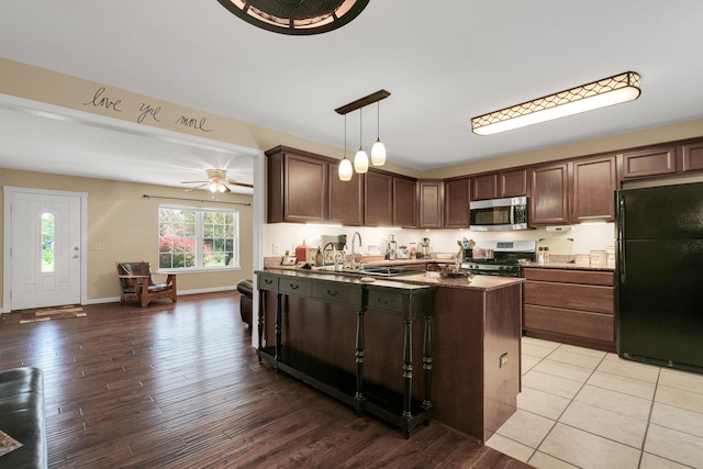 kitchen featuring a kitchen island, dark brown cabinets, decorative light fixtures, appliances with stainless steel finishes, and light hardwood / wood-style floors