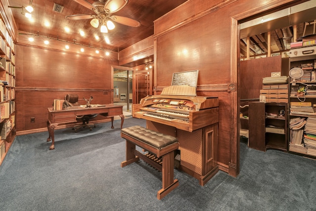 misc room with dark carpet, wooden walls, and ceiling fan