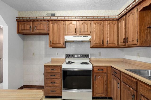 130 Wilshire Dr Unit 32, Hollister, MO 65672 - kitchen with white electric range, under cabinet range hood, brown cabinets, and a textured ceiling