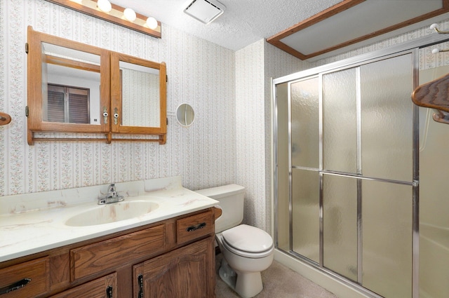 bathroom with a textured ceiling, walk in shower, vanity, and toilet