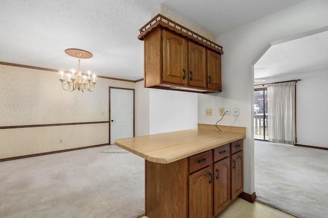 kitchen featuring a chandelier, light carpet, decorative light fixtures, kitchen peninsula, and a textured ceiling