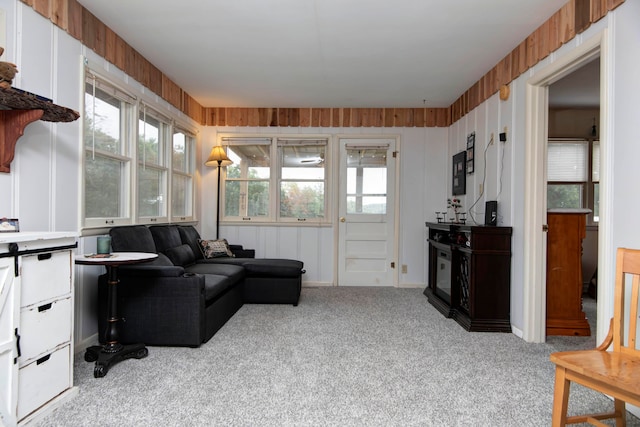 carpeted living room featuring wood walls