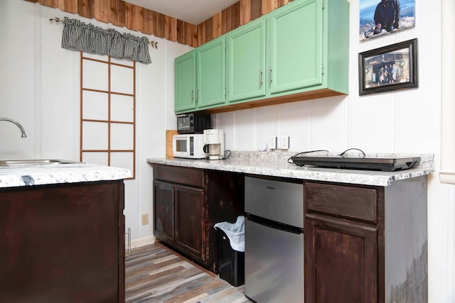 kitchen with green cabinetry, stainless steel refrigerator, hardwood / wood-style flooring, and sink