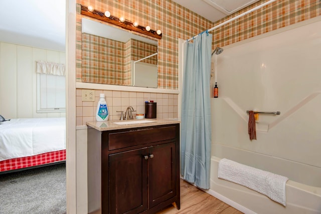 bathroom featuring shower / bath combo with shower curtain, hardwood / wood-style floors, vanity, and tile walls