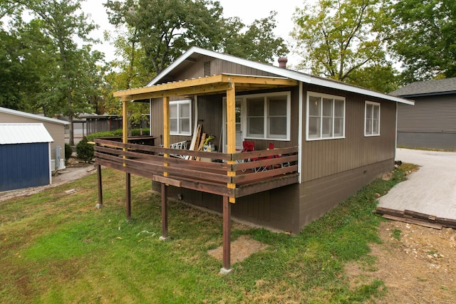 exterior space with an outdoor structure, a wooden deck, and a lawn