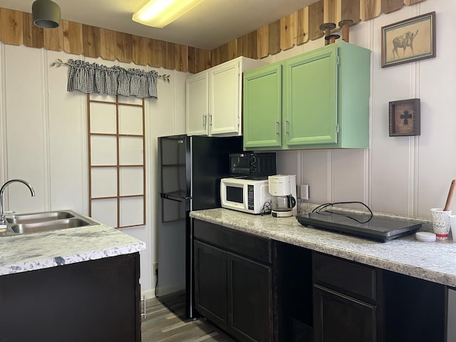 kitchen featuring hardwood / wood-style floors, sink, and black refrigerator