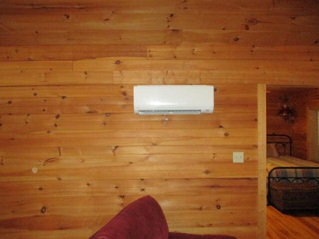 unfurnished room featuring a wall unit AC and wood-type flooring