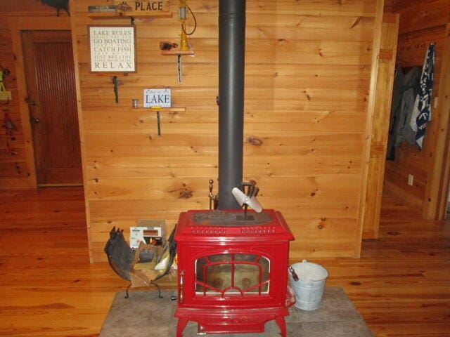 details featuring wood-type flooring, wooden walls, and a wood stove