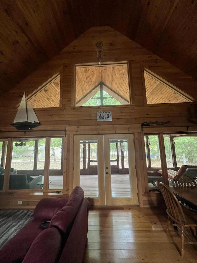 living room with high vaulted ceiling, wooden walls, french doors, wood-type flooring, and wooden ceiling