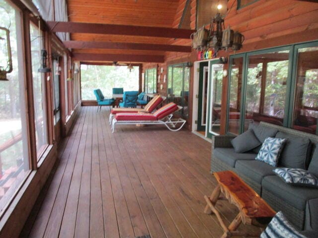 sunroom / solarium featuring lofted ceiling with beams and a chandelier