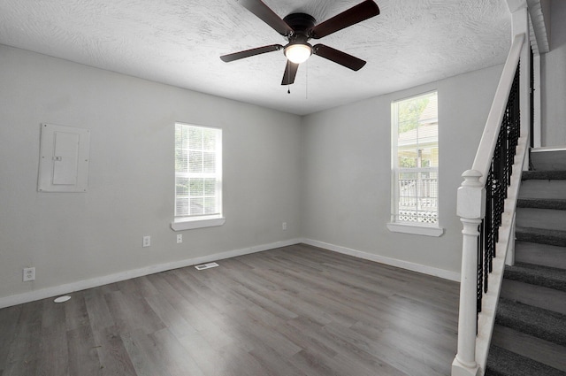 unfurnished room with electric panel, ceiling fan, wood-type flooring, and a textured ceiling