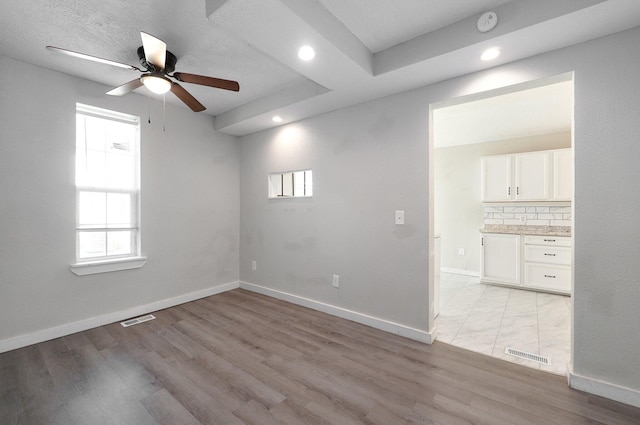 spare room with ceiling fan, a textured ceiling, and light wood-type flooring