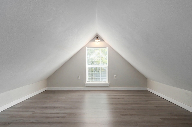 additional living space with a textured ceiling, lofted ceiling, and dark hardwood / wood-style floors