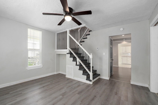 staircase featuring hardwood / wood-style flooring, ceiling fan, and a textured ceiling