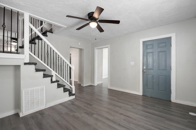 foyer entrance featuring ceiling fan, a textured ceiling, and dark wood-type flooring