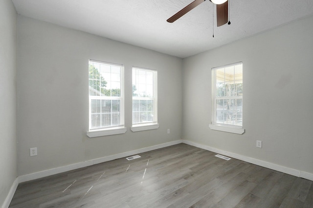 empty room with ceiling fan, a textured ceiling, and light wood-type flooring