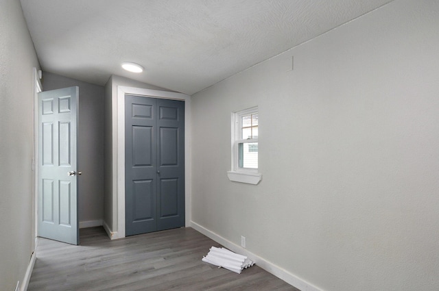 interior space featuring a textured ceiling, lofted ceiling, and light hardwood / wood-style floors