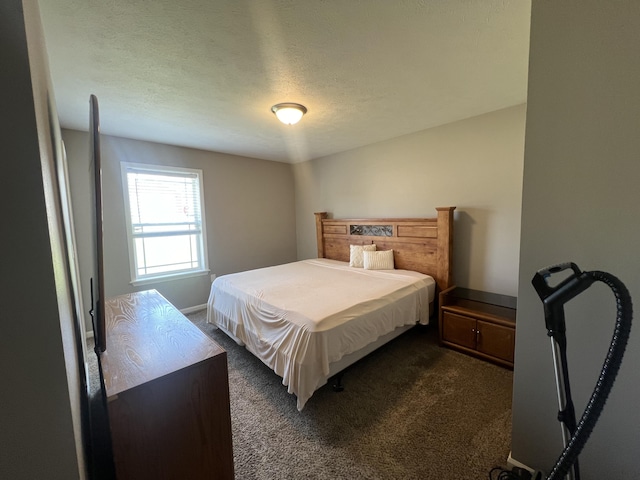 bedroom with a textured ceiling and dark colored carpet