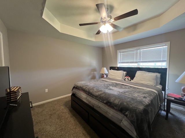 bedroom featuring ceiling fan, dark carpet, and a raised ceiling