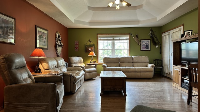 living room featuring a raised ceiling, hardwood / wood-style floors, and ceiling fan