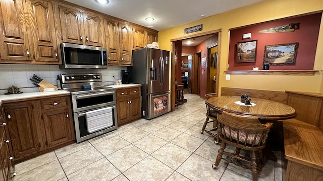 kitchen with light tile patterned flooring, stainless steel appliances, and tasteful backsplash