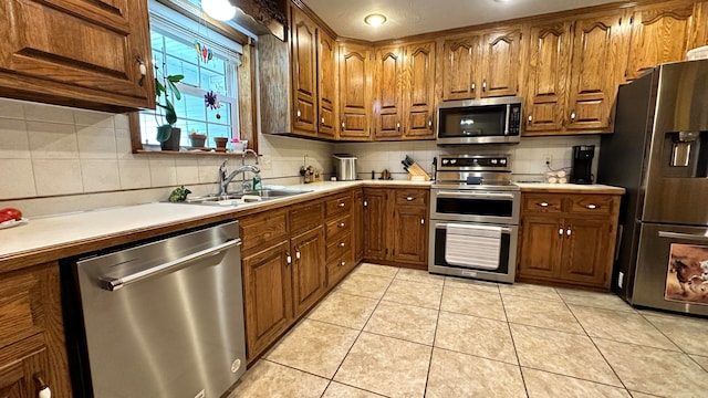 kitchen with light tile patterned flooring, appliances with stainless steel finishes, sink, and decorative backsplash