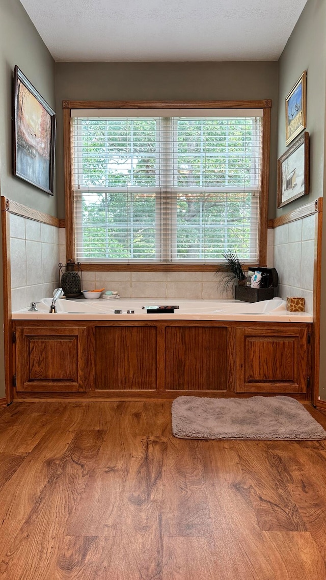 bathroom with wood-type flooring, a washtub, and a wealth of natural light