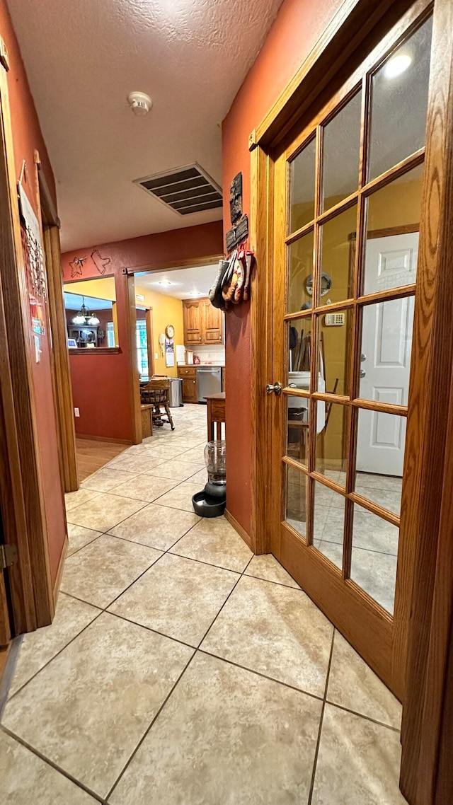 hall featuring light tile patterned floors and a textured ceiling