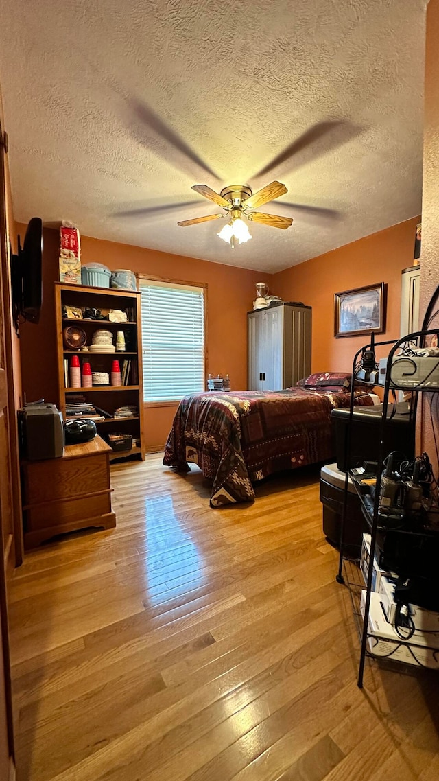 bedroom featuring ceiling fan, light hardwood / wood-style flooring, and a textured ceiling