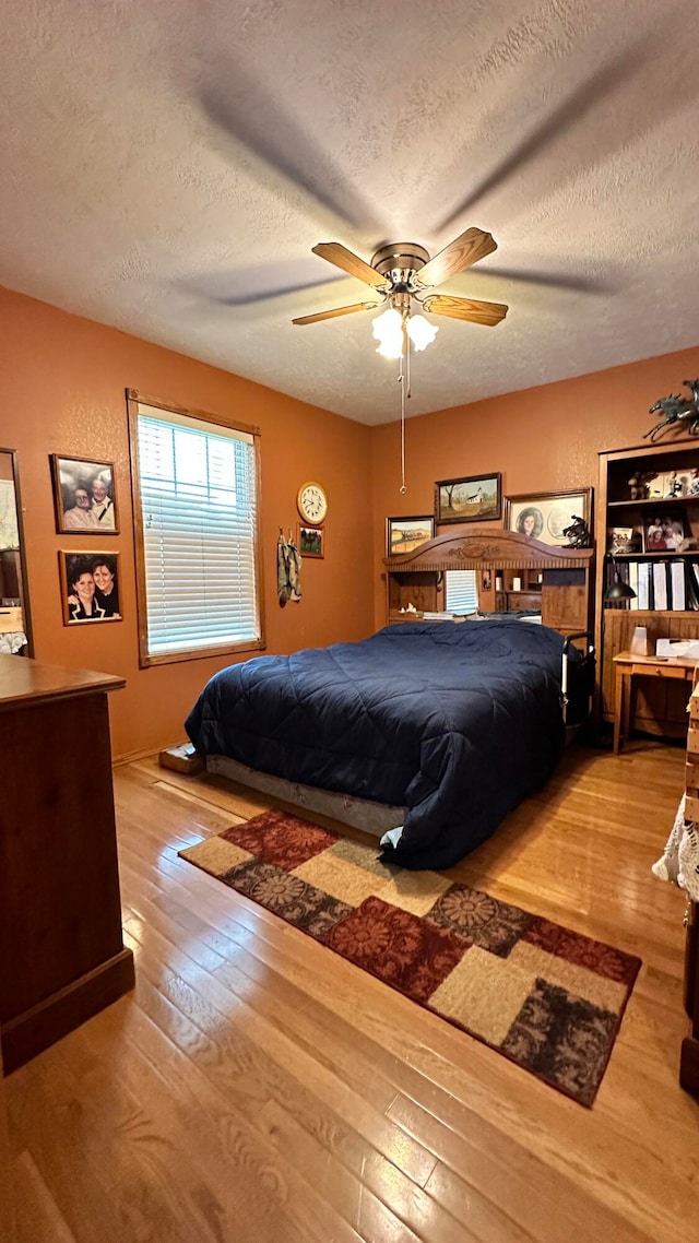 bedroom featuring light wood-type flooring, ceiling fan, and a textured ceiling