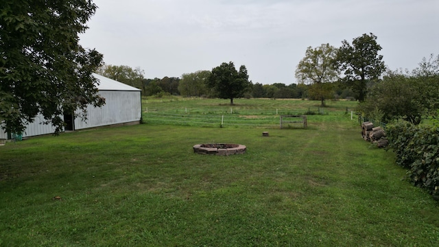 view of yard featuring a fire pit, an outdoor structure, and a rural view