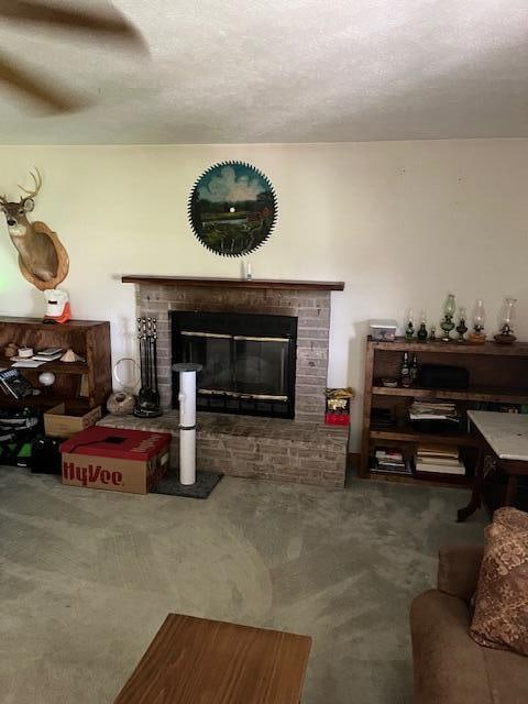 living room with a textured ceiling, a brick fireplace, and carpet flooring