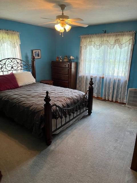 carpeted bedroom featuring multiple windows and ceiling fan