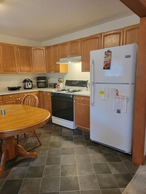 kitchen featuring light countertops, freestanding refrigerator, gas stove, and under cabinet range hood