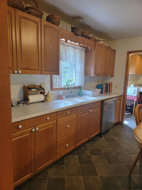 kitchen with dishwasher, brown cabinets, a sink, and light countertops