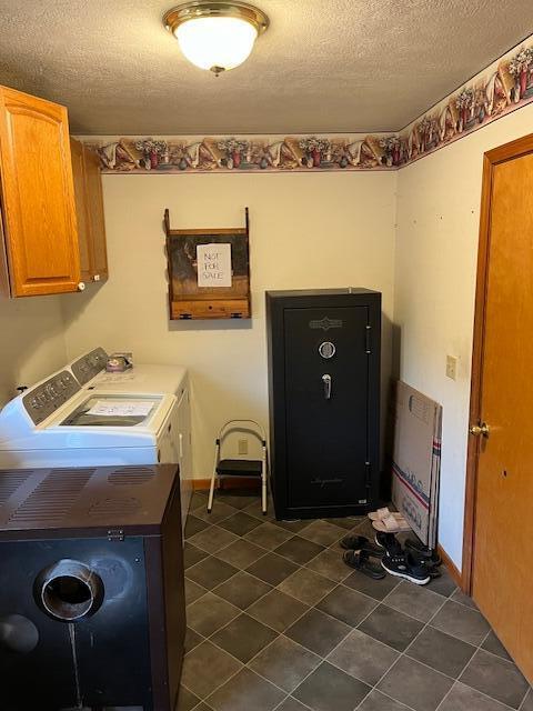 laundry area with washing machine and dryer, dark tile patterned floors, baseboards, cabinet space, and a textured ceiling