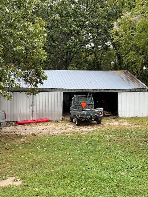 view of vehicle parking with a detached carport and an outbuilding