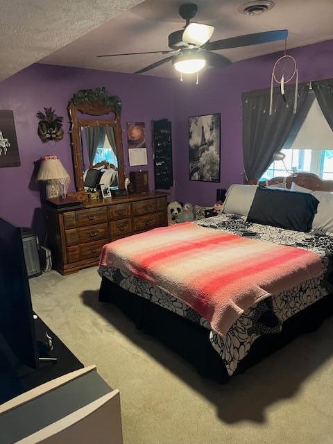 carpeted bedroom with ceiling fan and a textured ceiling