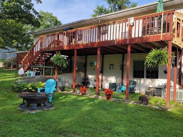 back of house with a fire pit, a yard, a wooden deck, and stairs