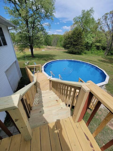 outdoor pool featuring a lawn and a deck