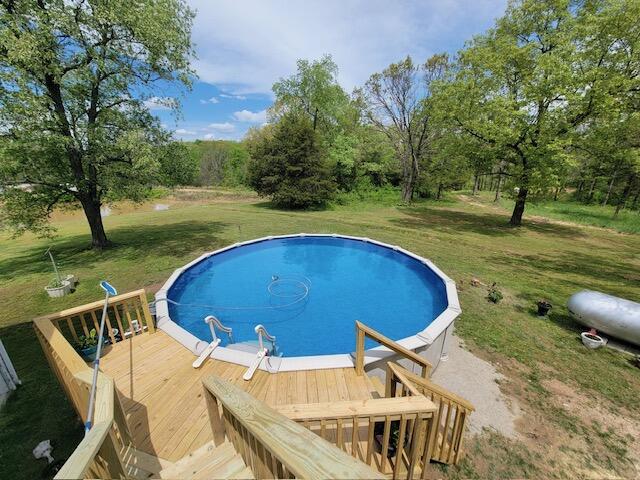 outdoor pool with a lawn and a deck