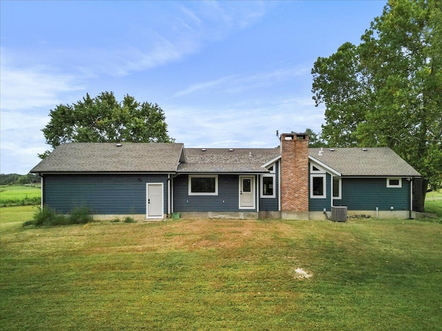 rear view of house with cooling unit and a lawn