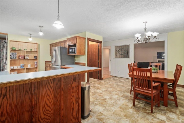 kitchen featuring appliances with stainless steel finishes, hanging light fixtures, an inviting chandelier, and a textured ceiling