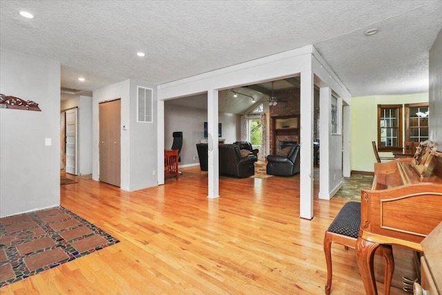 interior space featuring a textured ceiling, a fireplace, hardwood / wood-style floors, and lofted ceiling