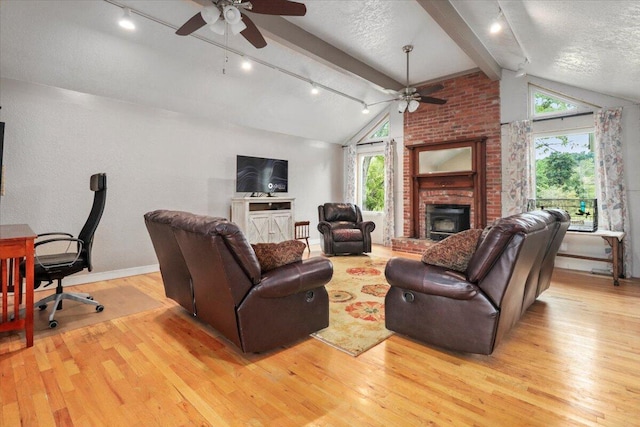 living room featuring ceiling fan, light hardwood / wood-style flooring, lofted ceiling with beams, and a wealth of natural light