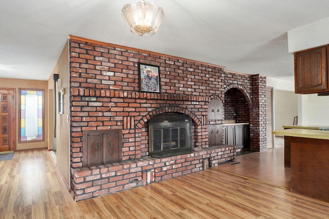 unfurnished living room with a fireplace, lofted ceiling, light hardwood / wood-style flooring, and a textured ceiling