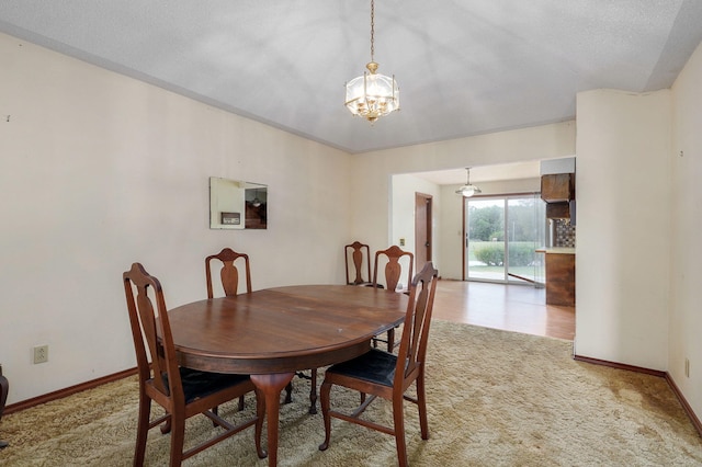 carpeted dining room featuring an inviting chandelier and a textured ceiling