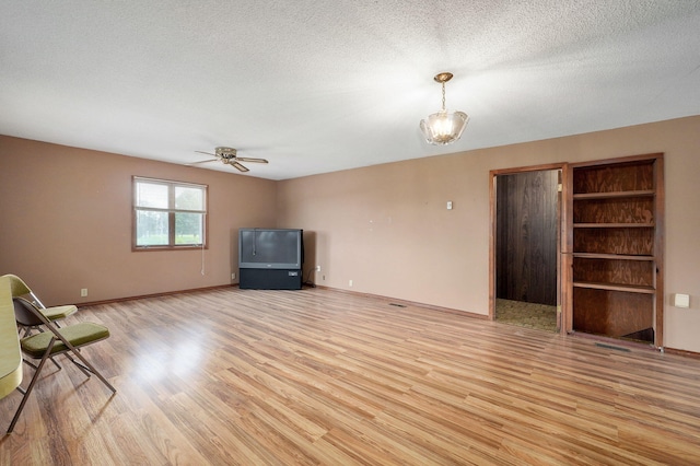 unfurnished living room with ceiling fan, a textured ceiling, and light wood-type flooring