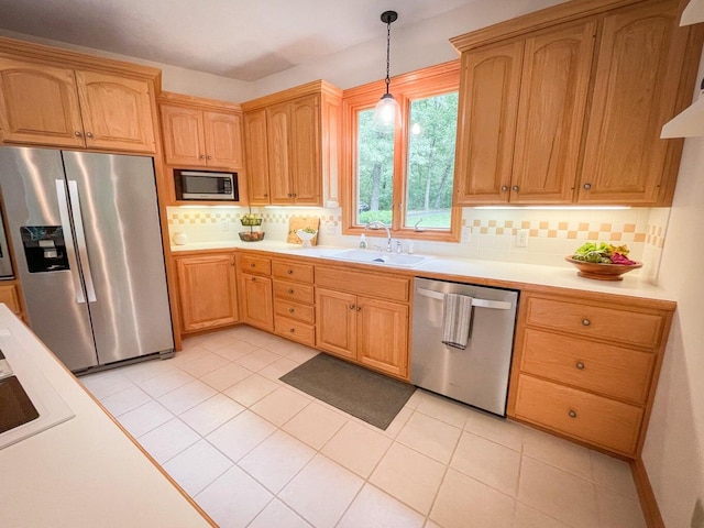 kitchen with sink, decorative light fixtures, light tile patterned flooring, decorative backsplash, and stainless steel appliances